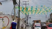 Una calle en donde se observan cables de luz, una camioneta, un coche blanco y uno rojo