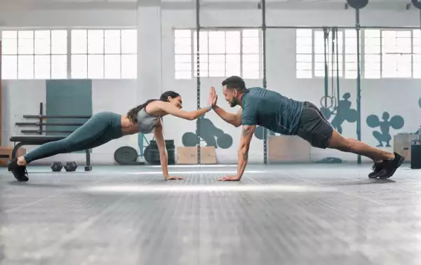 Fitness partners exercising together and doing pushups high five at the gym.