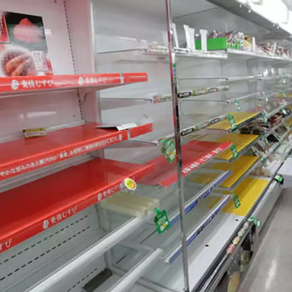 Una mujer busca provisiones en una tienda de Tokio, a pesar de que las tiendas muestran muy poca comida y agua.