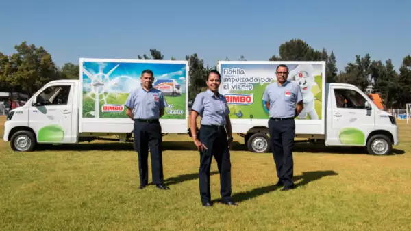 Se observan tres trabajadores de Bimbo frente a dos camiones de reparto. Grupo Bimbo, osito bimbo, mi ahorro bimbo