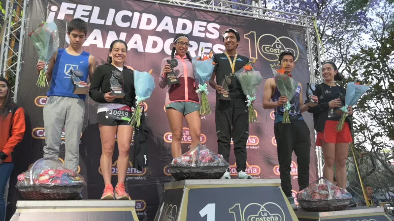 Personas ganadoras de la carrera con reconocimientos y flores.