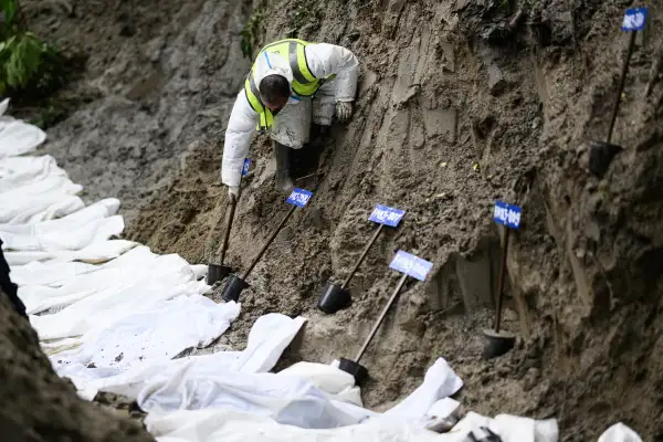 Un miembro del personal de seguridad coloca recipientes numerados junto a los cuerpos no identificados de víctimas de las inundaciones, preparados para una inhumación colectiva en la reserva forestal de Gokarna, en Katmandú, el 1 de septiembre de 2026.