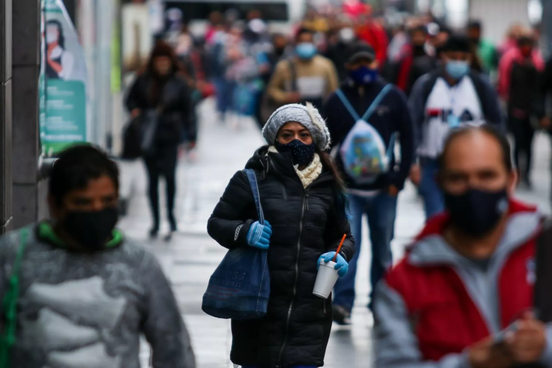 Personas con cubrebocas, chamarras y guantes transitan por el primer cuadro de la ciudad
