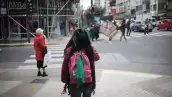 Persona no identificada caminando por la Avenida Corrientes con un pañuelo verde pro aborto en su mochila en Buenos Aires, Argentina