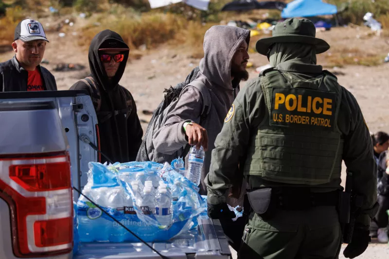 La patrulla fronteriza de Estados Unidos reparte agua a los migrantes que se han reunido entre las vallas fronterizas primaria y secundaria mientras los Estados Unidos se preparan para levantar las restricciones del Título 42 de la era de la COVID-19 que han impedido que los migrantes en la frontera entre Estados Unidos y México busquen asilo desde 2020 cerca de San Diego, California, Estados Unidos, 9 de mayo