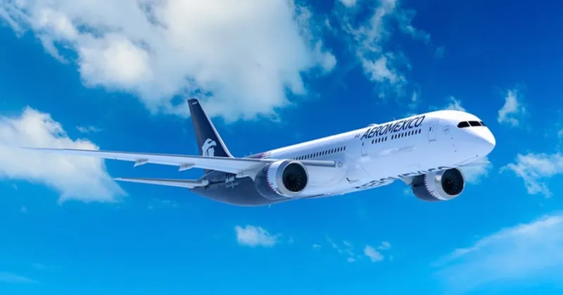 Un avión de color blanco con el logo de la empresa Aeroméxico surcando el cielo de color azul con blanco.jpg