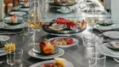 foto de una mesa de restaurante con elegantes platillos como langosta y mariscos y copas de vino blanco