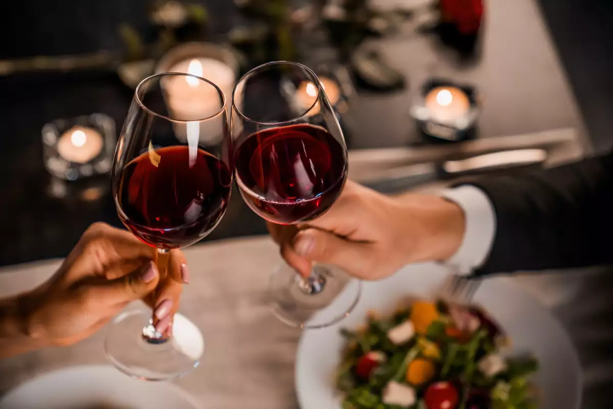 Una pareja brinda con vino tinto. Experiencias para festejar San Valentín
