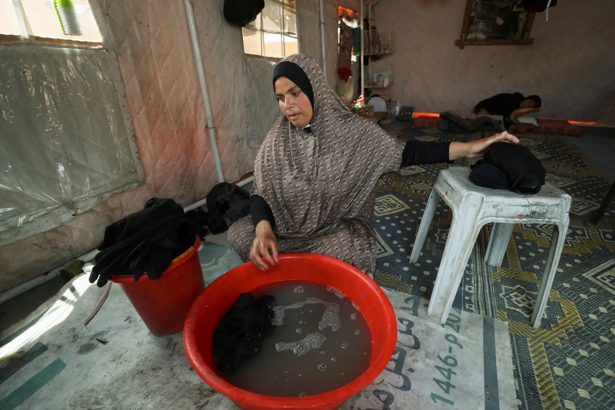 Mujer palestina, Mervat Hijazi, lava la ropa dentro de la tienda en la que se refugiaron después de ser desplazadas, en la ciudad de Gaza, el 22 de mayo de 2025.
