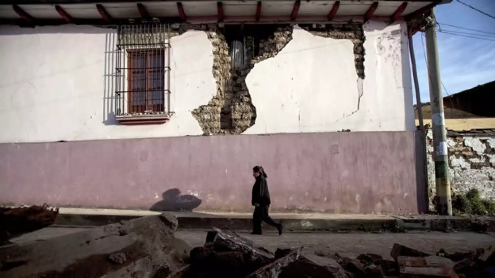 una mujer camina entre escombros