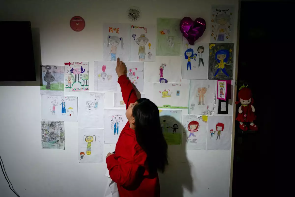 Casandra Fernández, hija de la enfermera Pamela Luciana Barraza Lucena, que trabaja en el hospital infantil Garrahan, un centro líder en cirugía pediátrica y trasplantes de órganos que ahora está en el corazón de la creciente crisis hospitalaria pública del país, señala un dibujo que hizo de su madre, en su casa en Buenos Aires, Argentina, el 13 de agosto de 2025.