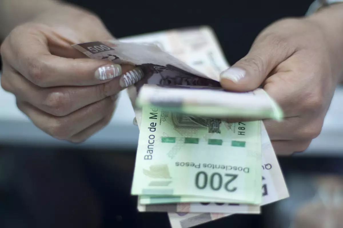 Te decimos cuántos días tarda el SAT en devolver el saldo a favor de la declaración anual. (Manos de una mujer contando dinero). 