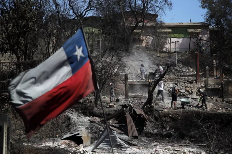 Una bandera chilena ondea mientras los vecinos limpian sus tierras y queman sus casas en Villa Independencia, región de Valparaíso, Chile, el 5 de febrero de 2024. El número de muertos por los incendios forestales en el centro de Chile aumentó a al menos 112 personas el domingo, después de que el presidente Gabriel Boric advirtiera que el número aumentaría "significativamente" a medida que los equipos buscan vecindarios destripados.