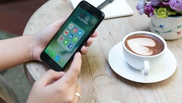 CHIANG MAI, THAILAND - NOVEMBER 14th, 2016: Hands using Iphone7 Plus jet black color with icons of social media on screen in coffee shop with latte art