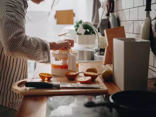 Millennial asian woman making a orange juice in morning