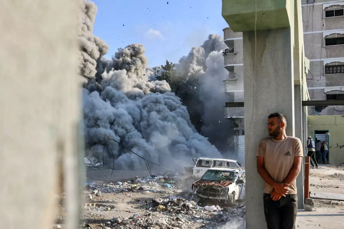 Un hombre se cubre detrás de una columna mientras una explosión propaga humo y polvo durante un ataque israelí que supuestamente tuvo como objetivo una escuela en el distrito de Zeitoun en las afueras de la ciudad de Gaza, el 1 de septiembre de 2024, en medio del conflicto en curso entre Israel y el grupo palestino Hamas.