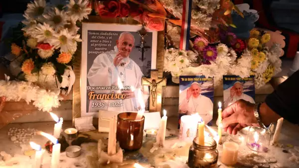 Velas y flores se colocan junto a las imágenes del difunto Papa Francisco en la entrada de la Catedral de Buenos Aires el 21 de abril de 2025.