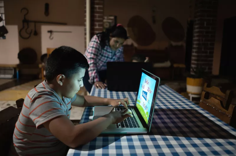 Latin American kids studying at home using laptop computers