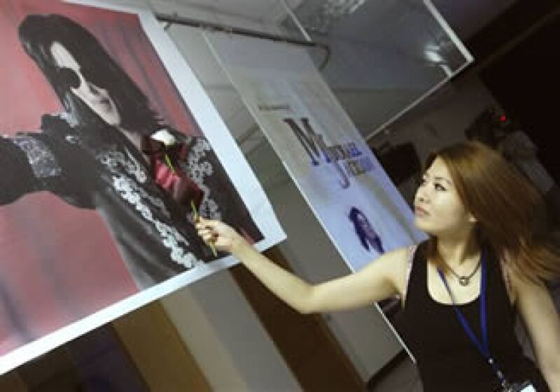 Una taiwanesa seguidora de Michael Jackson acerca una rosa blanca a un retrato del astro (AP).
