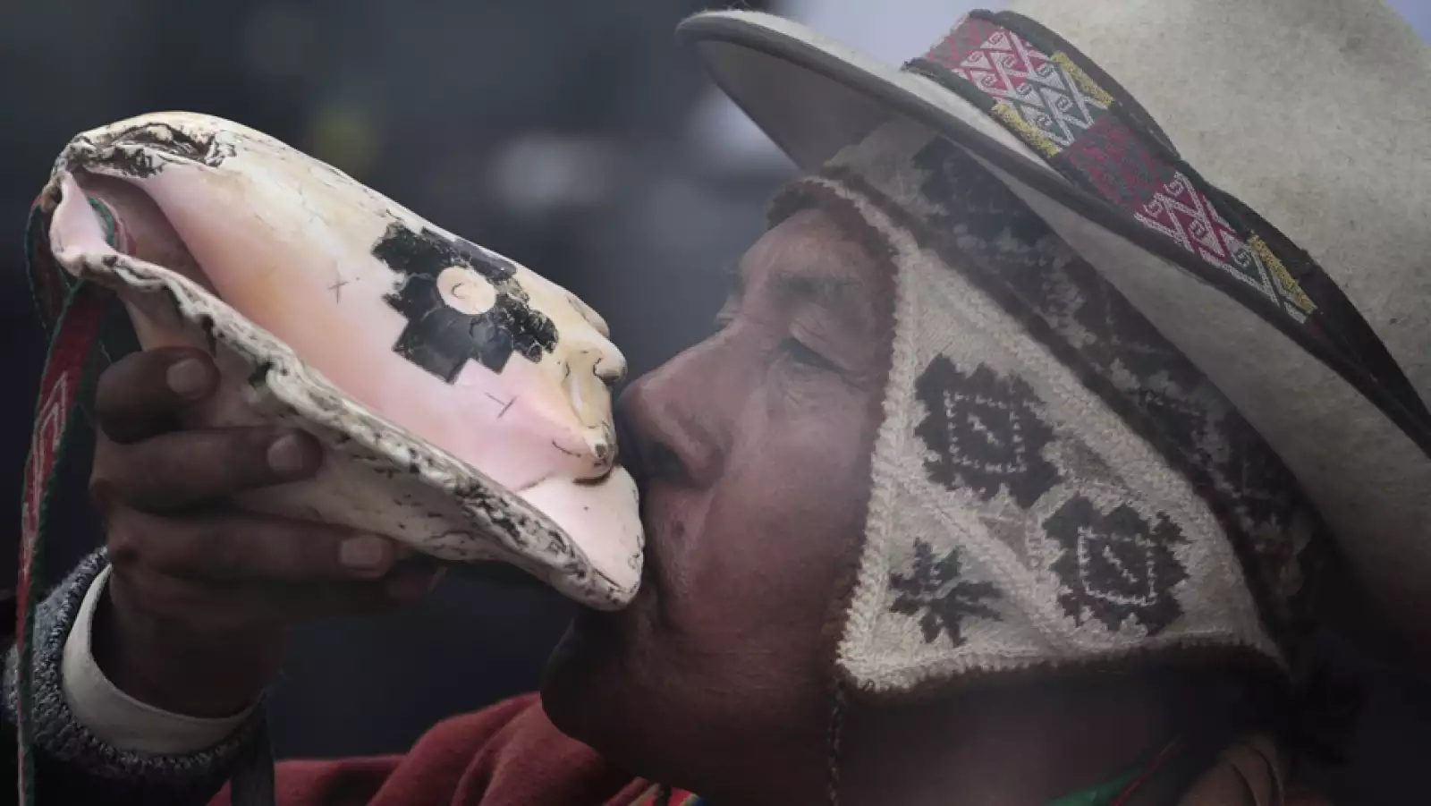 un boliviano hace sonar una concha durante el lanzmiento del satelite tupac katari