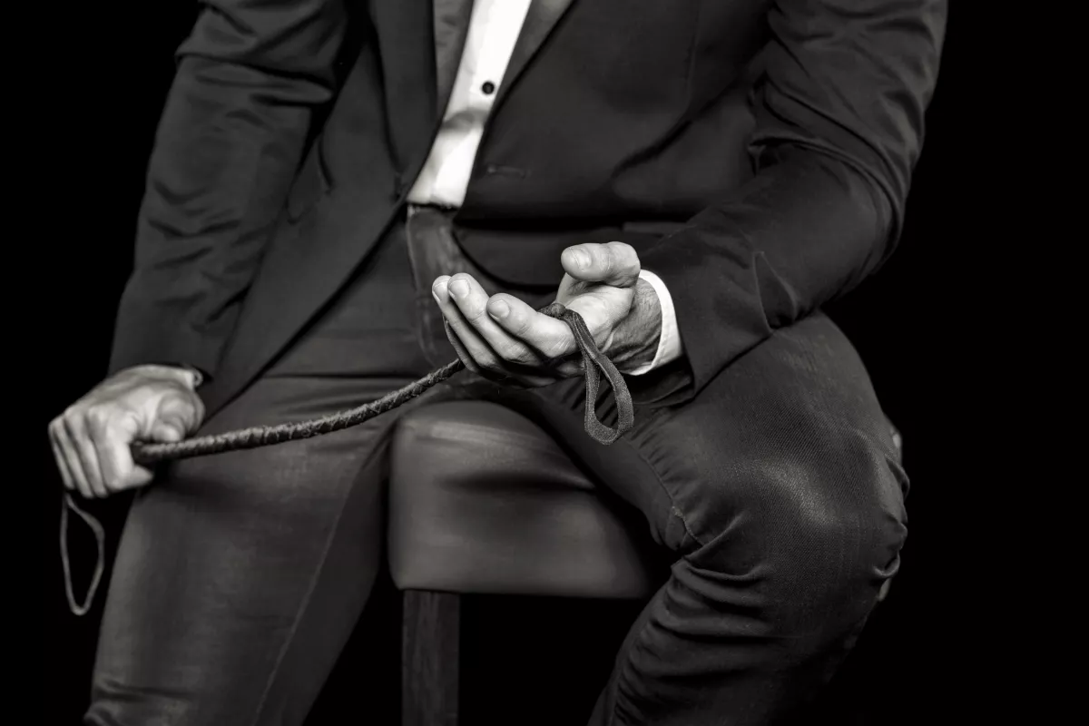 Rich,Man,Sitting,On,Bar,Stool,And,Holding,Whip,,Black