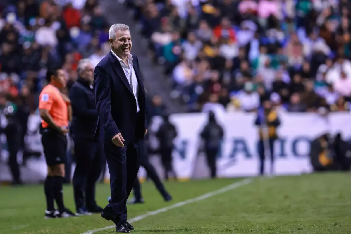 Foto de Javier Aguirre vistiendo traje oscuro y camisa blanca en el campo de futbol mientras dirige a su equipo en el encuentro México vs Valencia de octubre de 2024.