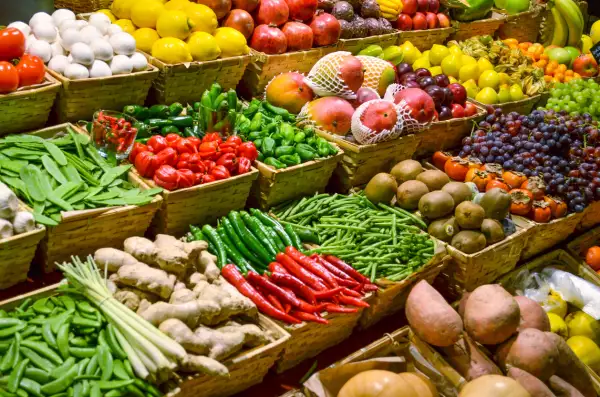 foto de un puesto de mercado lleno de frutas, verduras y legumbres, como kiwis, mangos, jengibre, chiles, limones, entre otros.