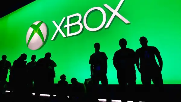 Asistentes a panel de Xbox posan frente al logo de la marca.