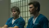 Foto de una escena de la serie "La historia de Lyle y Erik Menéndez" de Netflix, donde se ve a los actores que interpretan a los hermanos con ropa de presidiarios dentro de una celda.
