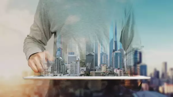 a man working on digital tablet, with Hologram futuristic modern buildings. City sunrise background