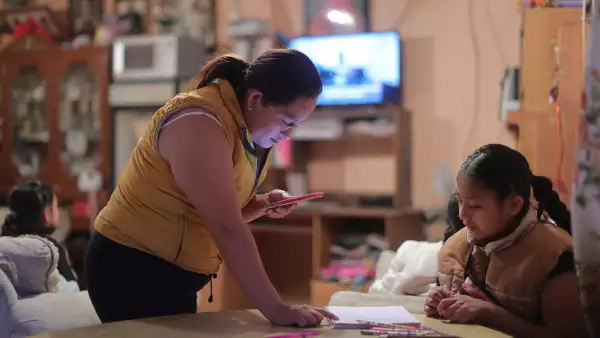 (Una mujer ayuda a su hija a hacer la tarea en su computadora)