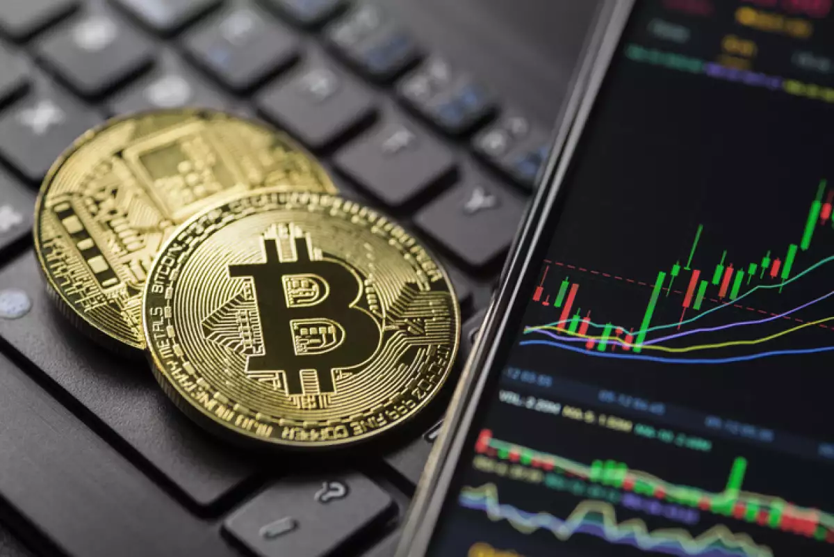 moneda con logo de bitcoin al lado de una gráfica de velas ascendente.