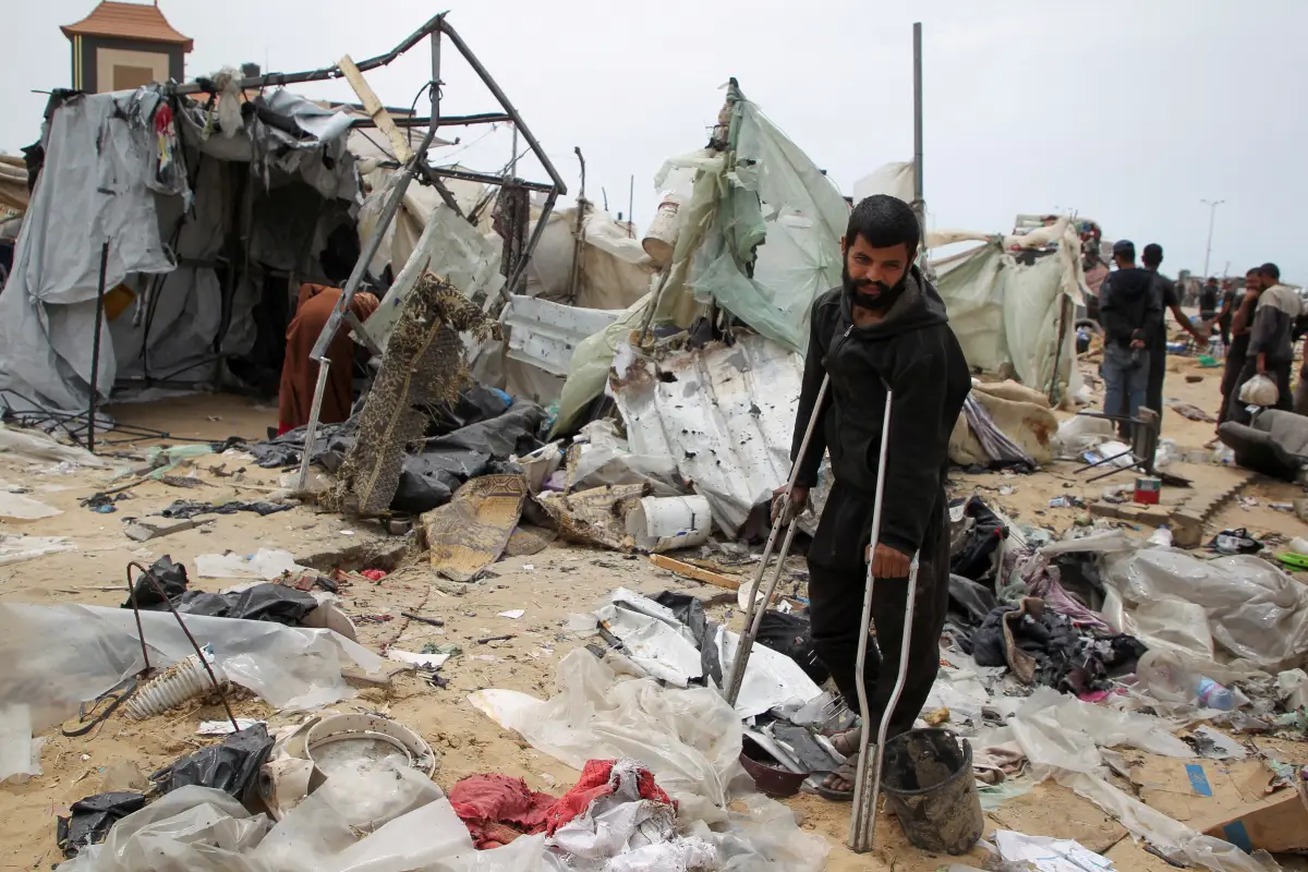 Un hombre observa mientras los palestinos inspeccionan un campamento de tiendas de campaña dañado en un ataque israelí durante una operación militar israelí, en Rafah, en el sur de la Franja de Gaza, el 28 de mayo de 2024.