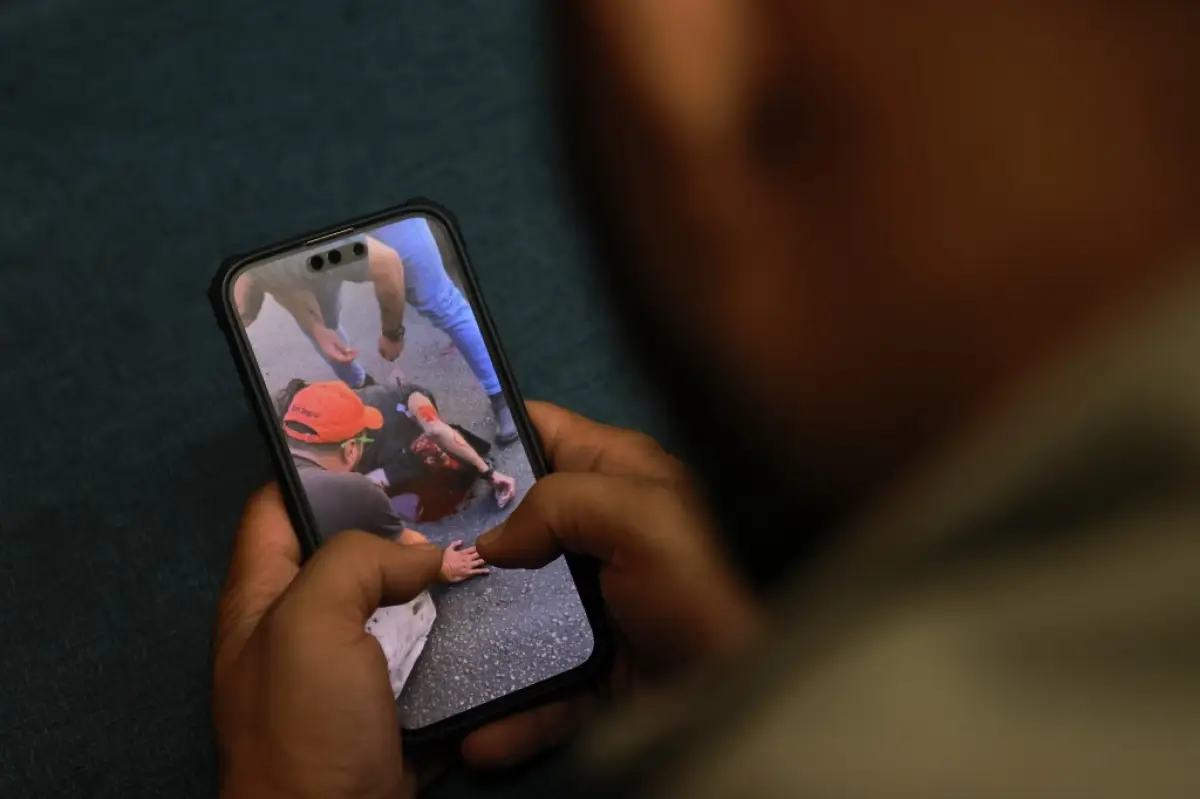 Un hombre ve un vídeo, publicado en las redes sociales, que muestra a un hombre herido el 17 de septiembre de 2024, después de que las explosiones golpearan lugares en varios bastiones de Hezbolá alrededor del Líbano en medio de las continuas tensiones transfronterizas entre Israel y los combatientes de Hezbolá.