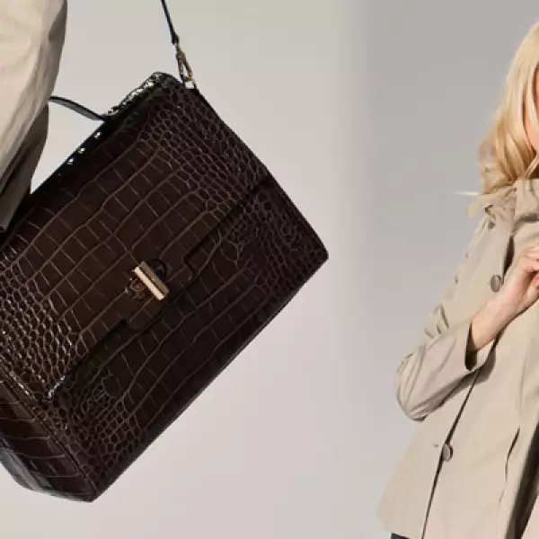 Un toque mucho más casual con esta gabardina en color crema, con botones dobles al frente y una bolsa que simula textura de piel de cocodrilo.