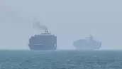 Esta toma de fotogramas tomada de las imágenes de vídeo de AFPTV del 12 de julio de 2026 muestra a los buques de carga anclados cerca del Estrecho de Ormuz, frente a la costa este de los Emiratos Árabes Unidos en Khor Fakkan
