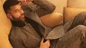 Ricky Martin posa en su casa de Los Ángeles. El cantante puertorriqueño se le ve recostado en un sillón vistiendo un traje gris. 