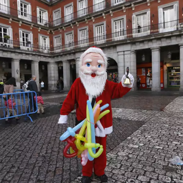 En una plaza de Madrid, España, un hombre se viste de Santa Clos para vender globos.