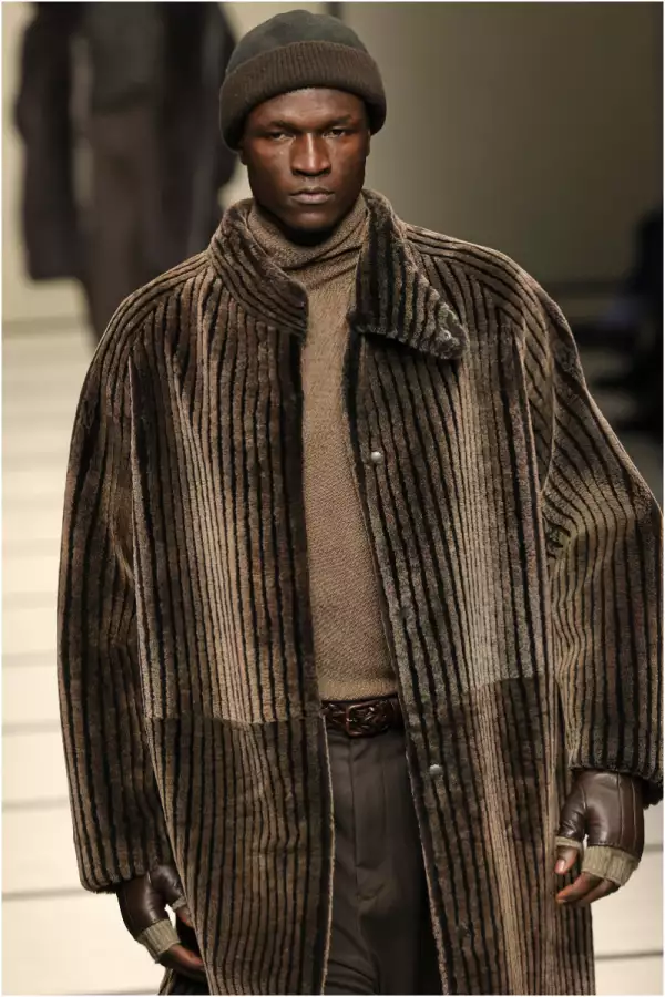 Foto de un modelo de armani en la pasarela con un gorro tipo binnie café y un abrigo de terciopelo del mismo tono.