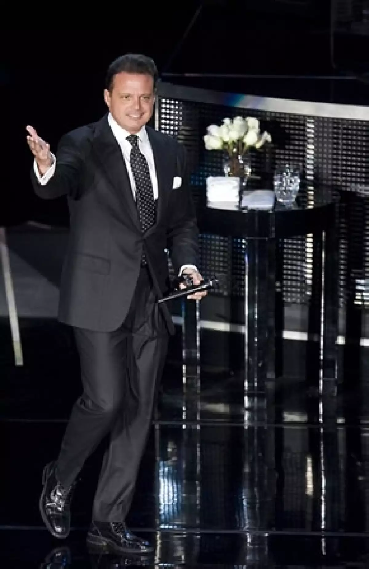 En el escenario había una mesa con tres vasos de agua, toallas y un florero con rosas blancas.