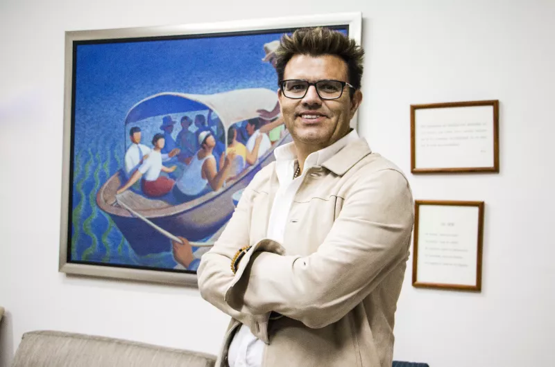 Petroil Amado Guzmán, detrás de él se observa un cuadro colgado en una pared y unos reconocimientos.