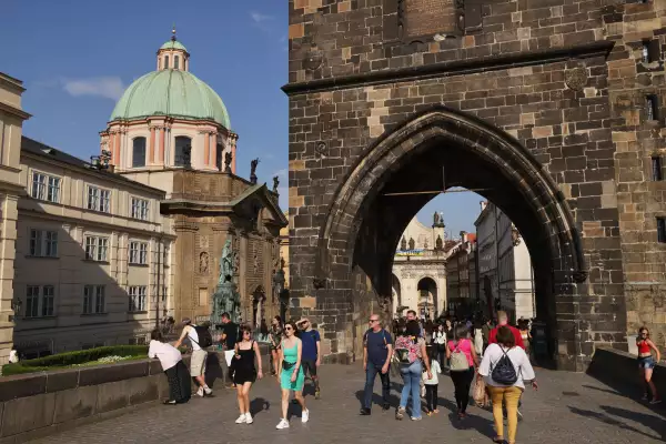 La gente camina bajo la Torre del Puente de la Ciudad Vieja en el Puente de Carlos el 14 de julio de 2022 en Praga, República Checa. La capital checa está viendo un fuerte aumento en el número de turistas visitantes después de la caída de los recientes años de Covid, aunque la ciudad aún no ha alcanzado los niveles anteriores a 2019