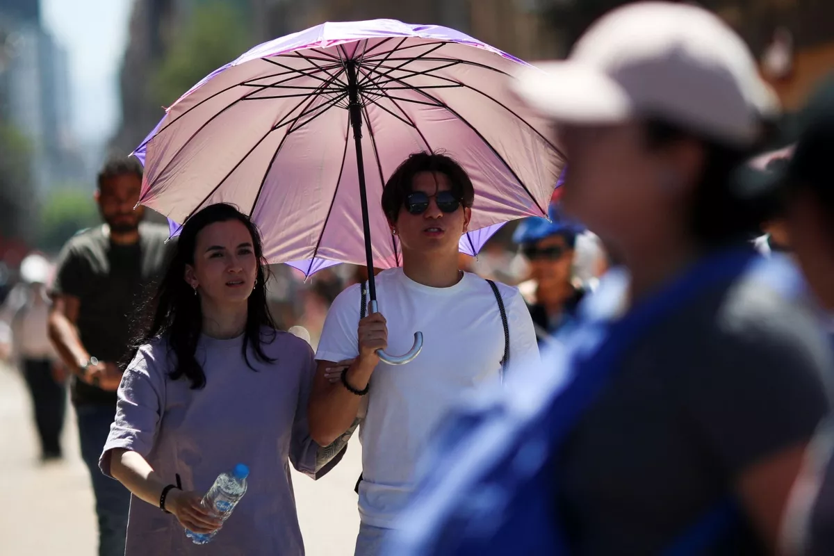 Personas en la calle se protegen con una sombrilla de la tercera ola de calor en México