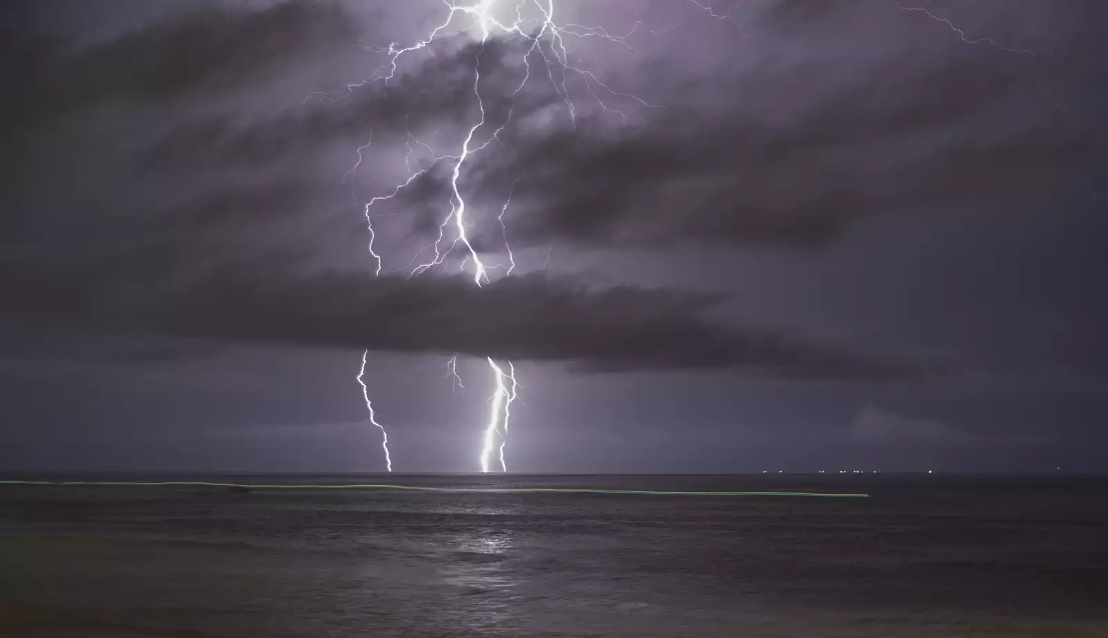 Una pequeña embarcación deja un rastro de luz en el mar para después cruzar la frontera de forma presuntamente ilegal.
