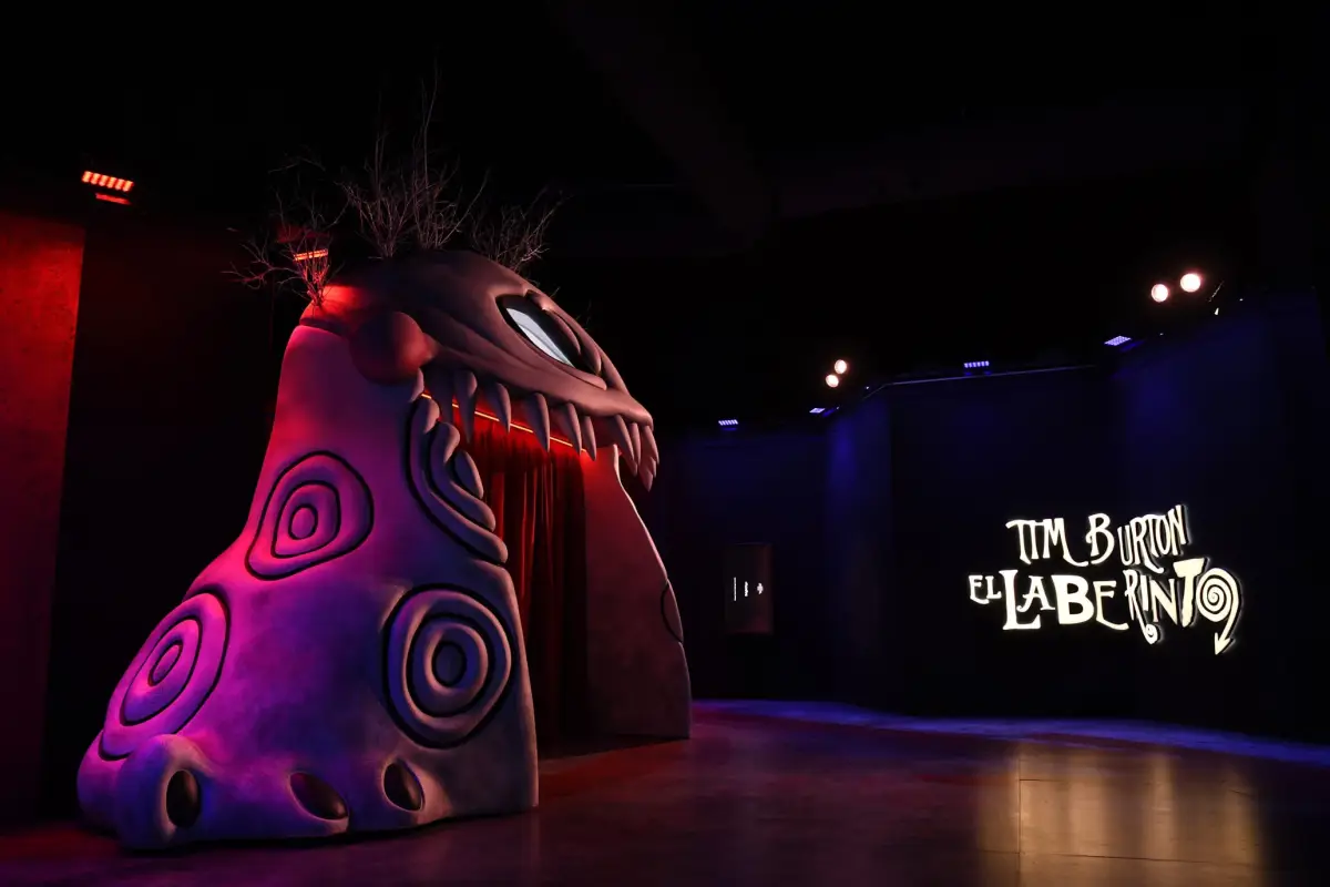 Foto de un personaje de Tim Burton en tamaño real, como parte de la exposición del cineasta. Al fondo un letrero iluminado que dice "Tim Burton El Laberinto".