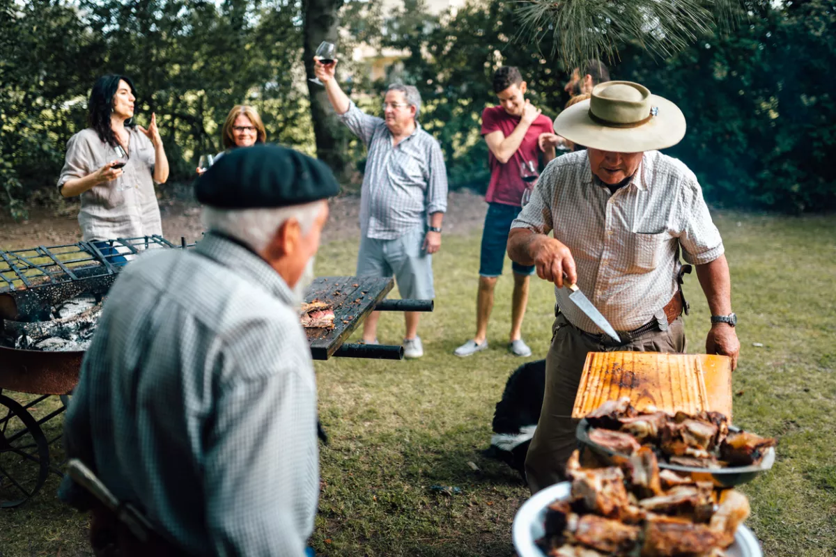 Foto de una familia argentina asando carne en un jardin al aire libre
