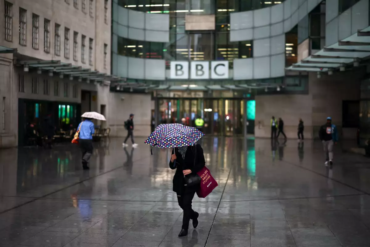 La gente se refugia de la lluvia fuera de la entrada a la BBC en Londres el 10 de noviembre de 2025. La directora ejecutiva saliente de BBC News dijo el 10 de noviembre de 2025 que la emisora "no era institucionalmente parcial", después de renunciar por acusaciones de que había editado engañosamente un discurso de Donald Trump. (Imagen principal del artículo web "La BBC se tambalea: renuncias, polémicas y una demanda de Trump por “difamación”"). 