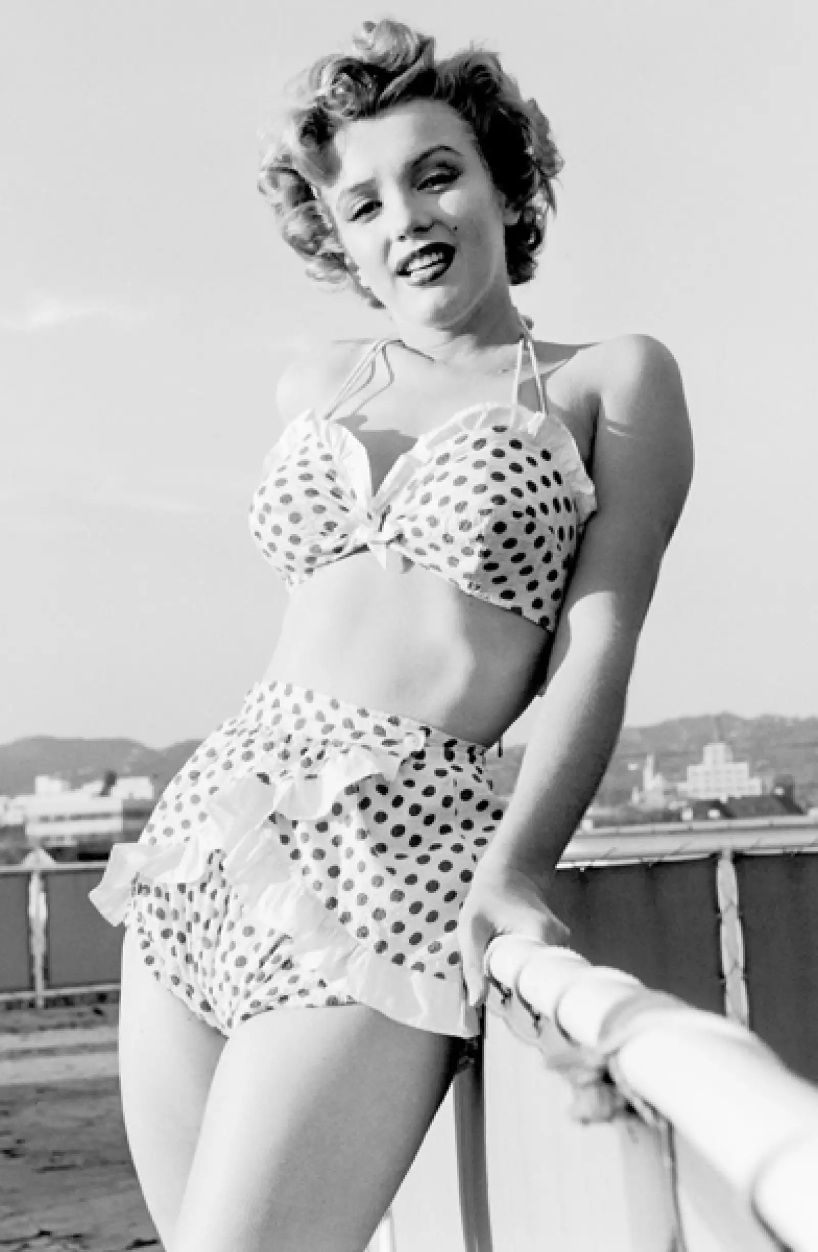 Muy femenina Marilyn Monroe en la década de los 50 con un conjunto muy femenino con holanes y lunares.