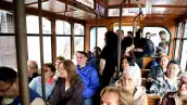 Interior de un tranvía en donde viajan 14 personas sentadas y cuatro paradas. El color del tranvía es café.jpg