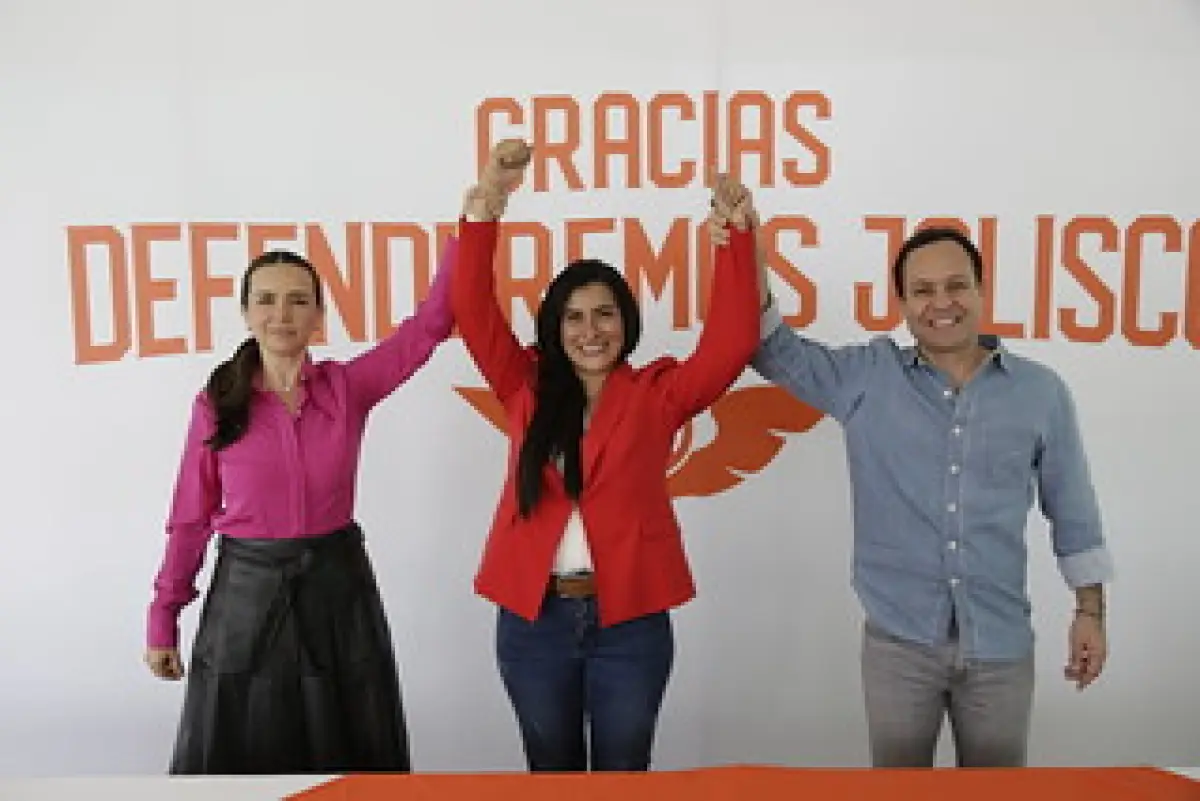 El dirigente de movimiento Ciudadano, Clemente Castañeda, está a la izquierda en una mesa con un mantel blanco y largo, acompañado de dos integrantes mujeres del partido. A sus espaldas hay un letrero que dice "Gracias, defenderemos Jalisco".